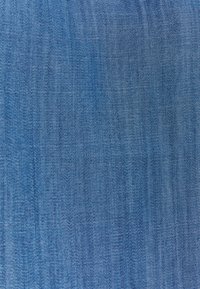 Tissu en denim d'une teinte bleu moyen, présentant une texture lisse avec un motif de toile en biais subtil. Aucun vieillissement visible ni embellissements.