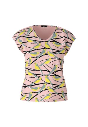 Oiseaux jaunes et gris perchés sur des branches noires imprimées sur un tissu rose, portés avec un pantalon jaune pâle et un bras visible.
