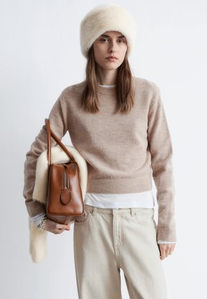 Beige knitted sweater with ribbed cuffs, cream faux fur hat, light beige wide-leg pants, and a brown leather bag with a zippered top.