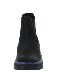 Botín negro de tobillo con parte superior de cuero suave, paneles laterales elásticos y suela de goma morada. Presenta una puntera redondeada y un diseño minimalista.