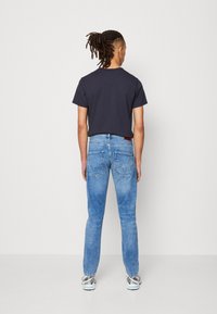 Marintröja med kort ärm i marinblått, kombinerad med ljusblå denimjeans med raka ben och bakfickor som har sömdekor.