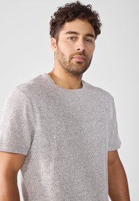 Maglione a maniche corte grigio chiaro in maglia, caratterizzato da un tessuto testurizzato e un collo rotondo, con una vestibilità comoda e leggero dettaglio a costine.