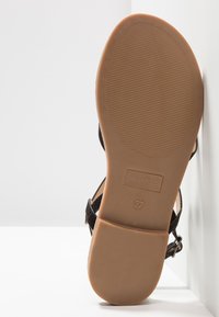 Musta mokkanahkakengät, joissa on säädettävä nilkkahihna, litteä tanssirotanpohja ja koholla oleva brändimerkintä. Kannan koko 37.