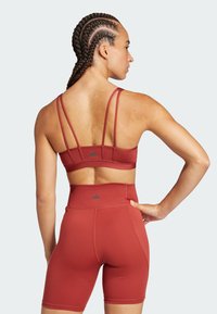 Sujetador deportivo rojo con tirantes finos y pantalones cortos de cintura alta en color a juego. Hecho de una tela suave y elástica con acentos de logo.