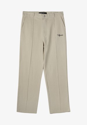 Beige tekstiililaid pantsid, mis on lõdva istuvusega, esitaskud ja üks tagatasku, ning vasakul reitel tikitud logo.