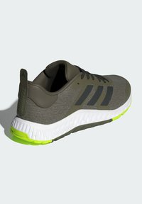 Grauer Sportschuh mit strukturierter Oberseite, schwarzen Akzenten und einer weißen, limonengrünen Gummisohle. Verfügt über eine Zuglasche an der Ferse.