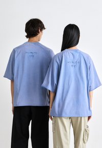 Ljusblå överdimensionerade t-shirts med broderad "MILANO EST 1978" på baksidan. Har korta ärmar och en avslappnad passform.