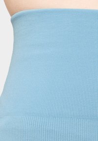 Světle modrá žebrovaná látka tvoří přiléhavý pas s hladkým povrchem. Design je jednoduchý a bezšvový, zdůrazňující elastický materiál.