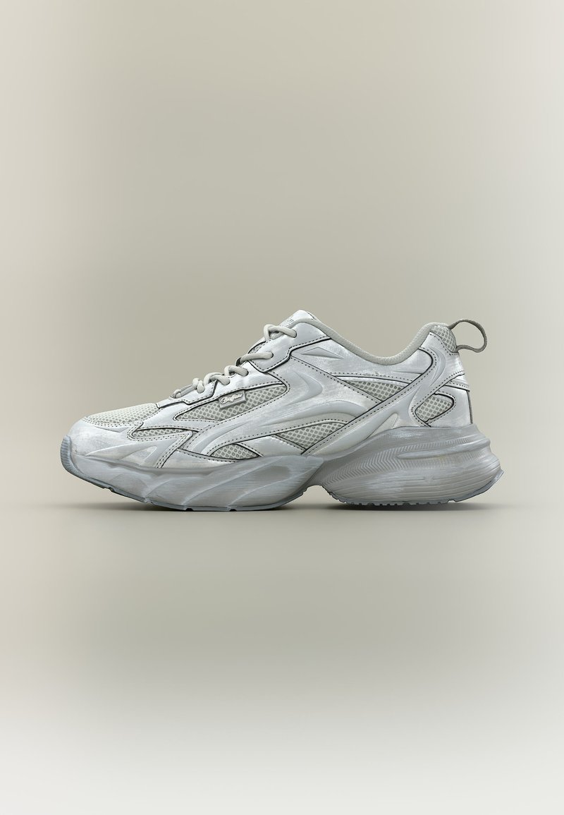 Biely a sivý športový teniska s panelmi z priedušnej sieťoviny, hrubou vyvýšenou podrážkou, šnurovacím dizajnom a pútkom na päte na neutrálnom pozadí.