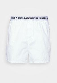 Biele bavlnené boxerky s jemnou textúrou, so modrým elastickým pásom so čiernym textom "KARL LAGERFELD" a jedným predným gombíkom.