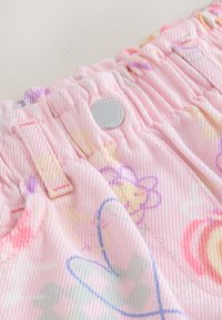 Pantaloni roz cu talie elastică, cu motive colorate de flori și inimioare, având un nasture argintiu în față, la centru.