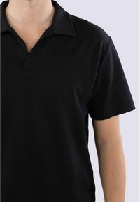 Sort polo skjorte lavet af tekstureret materiale med en V-formet krave, korte ærmer og en afslappet pasform. Ingen synlige mønstre eller hardware.