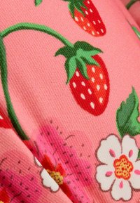 Roza tkanina z živahnimi rdečimi jagodami ter zelenimi listi in cvetovi. Teksturan površina z cvetličnim vzorcem in svetlimi barvami.