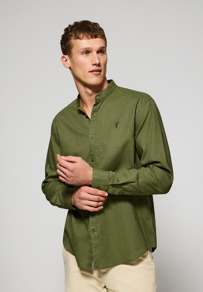 Groene langwerpige blouse met een button-down kraag, met een subtiele textuur en een klein logo op de borst. Gladde katoenen stof.