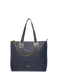 Bolso tote de cuero azul marino con patrón de logo en relieve, doble asa superior y un detalle de cadena en tono dorado. Presenta un amplio compartimento principal.