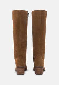 Botas de ante marrón hasta la rodilla con tacón apilado, cremallera trasera, textura suave y costuras definidas. Diseño sencillo y clásico.