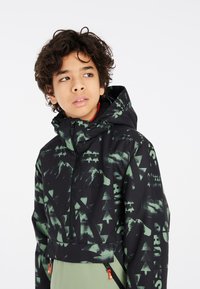 Giacca con cappuccio a motivo nero e verde, caratterizzata da design di montagne e alberi. Chiusura frontale con zip e dettagli in un vivace arancione.