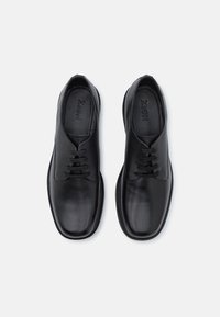 Zwarte leren schoenen met een gladde afwerking, ronde neus en vetersluiting. De binnenkant heeft een comfortabele binnenzool en een merkinterieur.