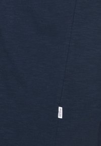 Marinblusig casual topp i strukturerad bomull, med en liten log etikett på sidan och en enkel, odekorerad design.