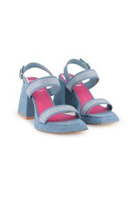 Sandalias de tacón alto de denim azul con dos tiras brillantes, una parte superior texturizada y una plantilla fucsia sobre un tacón cuadrado.