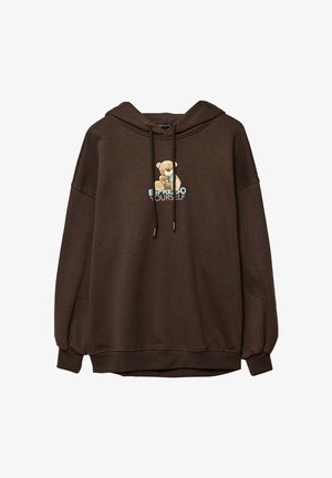 Brun huvtröja med en björnsgrafik och texten "UTTRYCK DIG SJÄLV" i ljusblått. Tillverkad av mjukt material med avslappnad passform och dragsko.