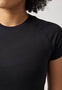 Zwarte sportieve t-shirt met een aansluitend ontwerp, korte mouwen, textuurstof en naadloze constructie, met een gladde halslijn.