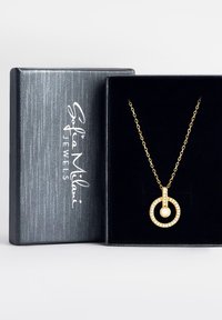 Guld halskæde med en rund vedhæng dekoreret med klare ædelsten, præsenteret i en sort velourforet æske med tekstureret ydre.