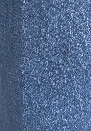 Tessuto in denim in diverse sfumature di blu, caratterizzato da una leggera texture con un sottile motivo a spina di pesce. La superficie appare liscia con alcune leggere punteggiature.