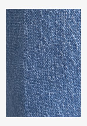 Tessuto in denim in diverse sfumature di blu, caratterizzato da una leggera texture con un sottile motivo a spina di pesce. La superficie appare liscia con alcune leggere punteggiature.