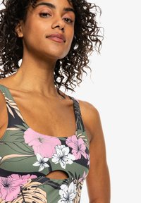 Maillot de bain fleuri multicolore avec un décolleté carré, des découpes et un mélange de teintes roses, blanches et vertes, le tout avec une texture lisse.