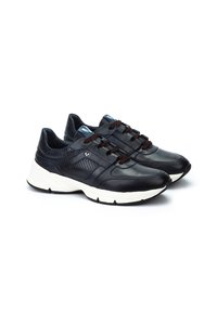 Musta nahkainen urheilukengät, joissa on teksturoitu verkko-paneeli, valkoinen pohja ja ruskeat nauhat. Ominaisuuksiin kuuluu pyöreä kärki ja minimaalinen brändäys.