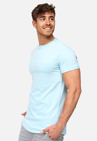 Camiseta de algodón de color azul claro con mangas cortas, escote redondeado, ajuste slim, que presenta un pequeño logo blanco en el pecho.