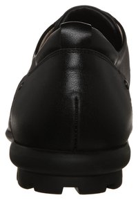 Black leather shoe rear view, featuring a smooth texture, rounded heel, and unique stitching detail. The sole has a rugged pattern for grip.