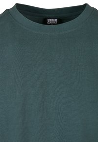 Mørk teal kortermet t-skjorte med ribbet rund hals. Stoffet ser glat og lett ut, og har en etikett merket "Urban Classics."