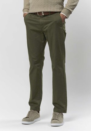Olivengrønne chinos lavet af bomuld med en glat tekstur, med sidelommer og en slank pasform, kombineret med beige ruskindsneaks.