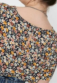Blusa floreale con sfondo nero, piccoli fiori in tonalità gialla, rosa e blu, design con apertura a chiave sul retro con dettaglio a bottone.
