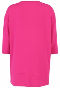 Long-sleeve top in bright pink, made of soft fabric. Features a relaxed, boxy fit and a curved hem at the bottom.