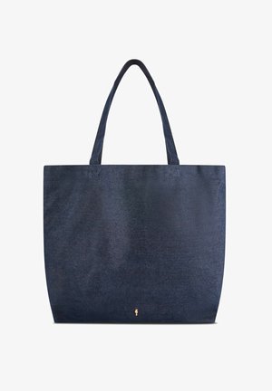 Granatowa torba typu tote z denimu z dwoma paskami na ramię i małym złotym logo w pobliżu dolnego środka.