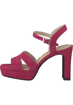 Fuchsia ruskind sandal med høj hæl og plateau, med krydsede remme, justerbar ankelrem med sølvspænde og tekstureret sål.