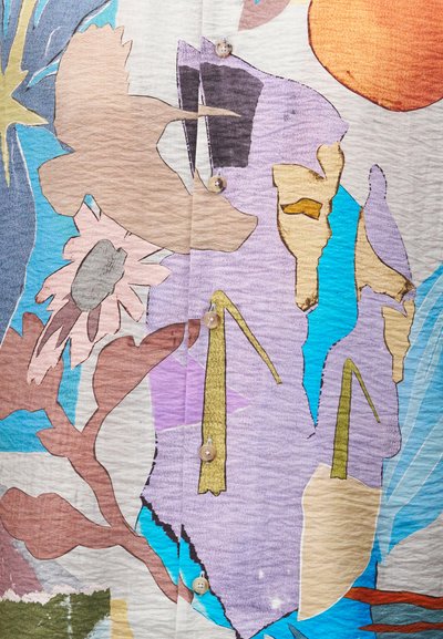 Αφηρημένες μορφές λουλουδιών και πουλιών σε παστέλ χρώματα σε ύφασμα με κουμπιά σε αποχρώσεις του μωβ, μπλε, πορτοκαλί, μπεζ και καφέ.