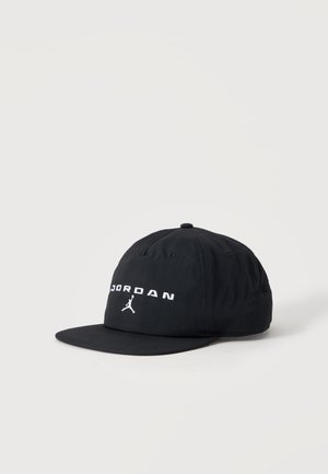 Casquette noire Jordan à visière plate avec logo blanc brodé et silhouette Jumpman sur le panneau avant sur fond uni.