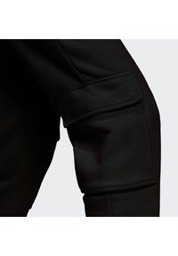 Pantalones cargo negros con un tejido suave y un acabado texturizado, parches en las rodillas y bolsillos laterales.