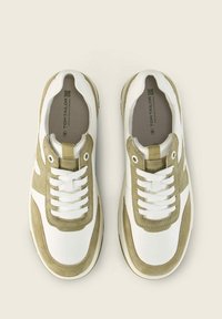 Baskets blanches avec des accents en suède vert olive, présentant un système de laçage, un bout rond et une semelle en caoutchouc texturée.