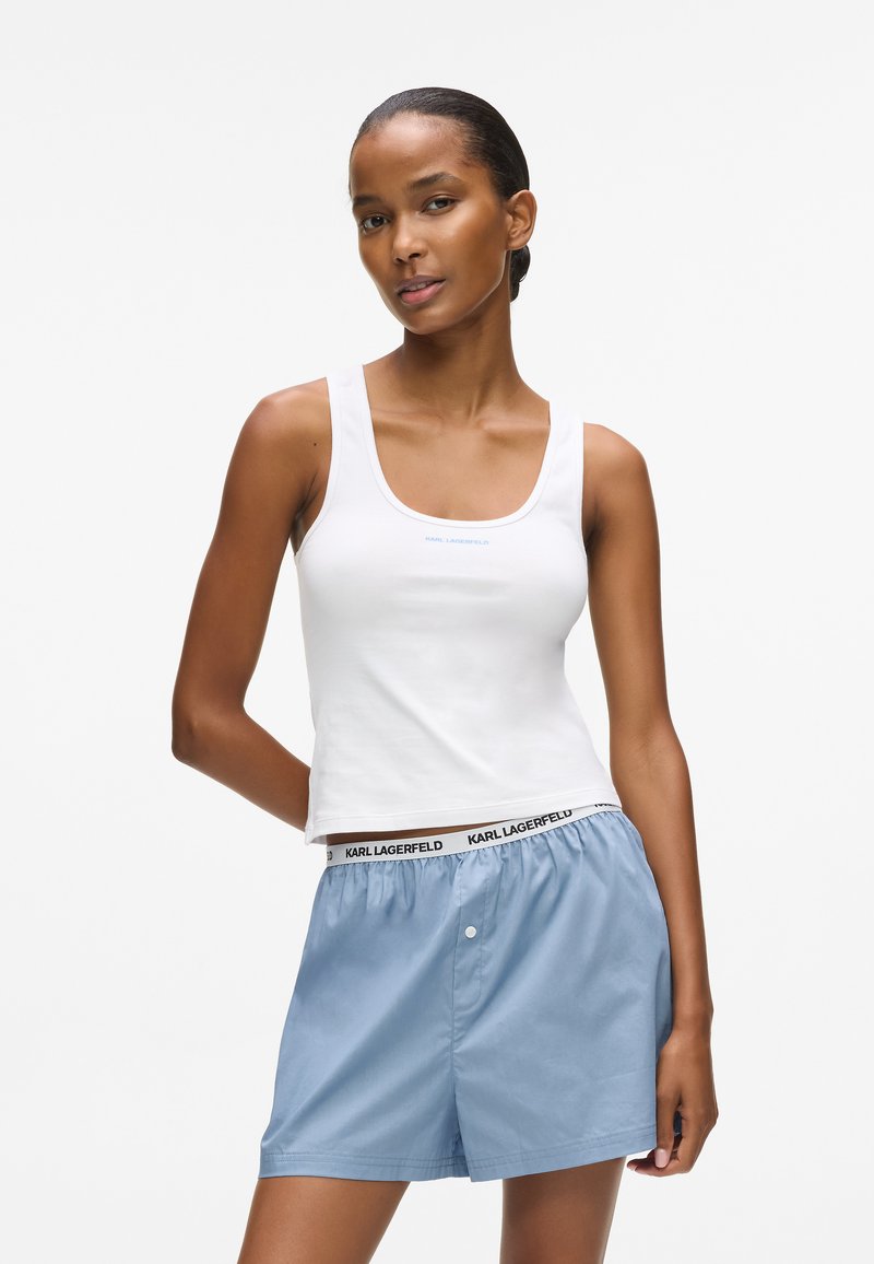 Balta iraginė marškinėliai su apvaliu iškirpimu ir šviesiai mėlynu logotipu. Suderinta su šviesiai mėlynomis šortais, turinčiomis elastingą juosmenį ir juodą logotipą.