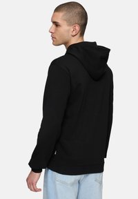 Felpa nera con finitura testurizzata, caratterizzata da una vestibilità aderente, cappuccio con coulisse e polsini a coste. Il design include un piccolo logo etichetta sull'orlo.