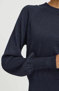 Dunkelblauer Pullover aus strukturiertem, leicht schimmerndem Strick mit Raglanärmeln und gerippten Akzenten an den Bündchen und am Ausschnitt.