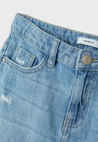 Hellblaue Jeansshorts mit klassischem Fünf-Taschen-Design, abgewetzten Akzenten und einem Metallknopfverschluss mit angenähter Etikette.