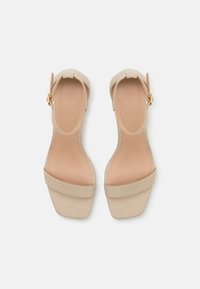 Beige suede korkokengät avonaisella varpaalla, leveällä nilkkaremmillä ja solkitekstuurilla. Ominaisuudet: teksturoitu päällinen ja sileä sisävuori.
