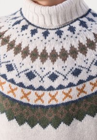 Sweter z dzianiny z prążkowanym kołnierzem; charakteryzuje się geometrycznymi wzorami w kremowym, niebieskim, brązowym, zielonym i pomarańczowym włóczkach. Miękka struktura.