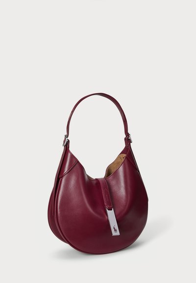 Burgundy leather shoulder bag with a curved shape, silver hardware accent, and smooth texture. Features a single, adjustable strap.